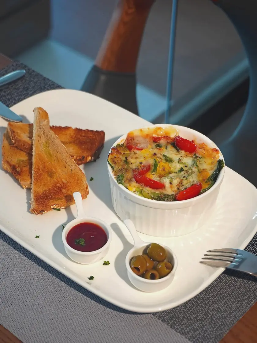 Baked eggs breakfast with toast, jam and olives